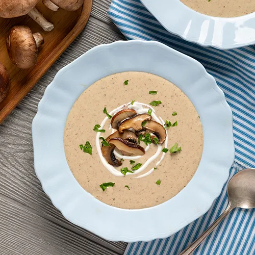 two white bowls housing cream of mushroom soup with mushroom topping