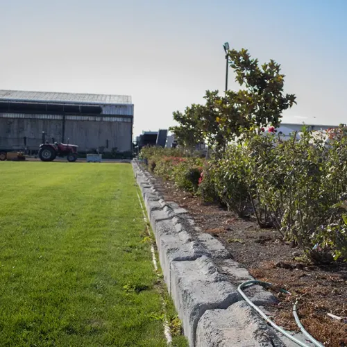 garden with retaining wall by some grass and farm machinery in the background