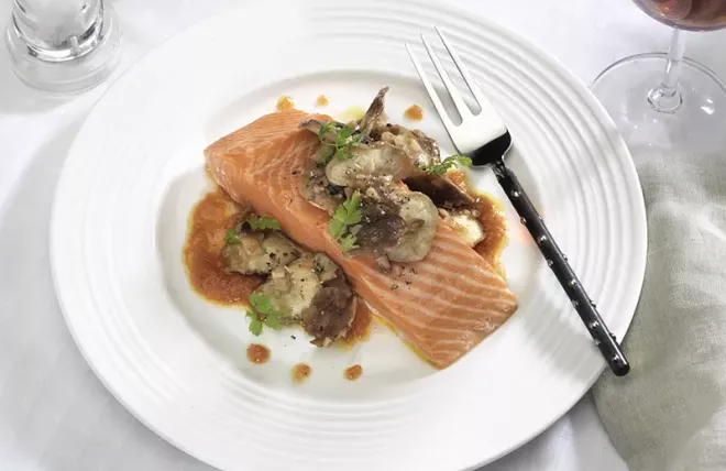 Cooked Salmon on white plate with Shiitake Mushrooms over top