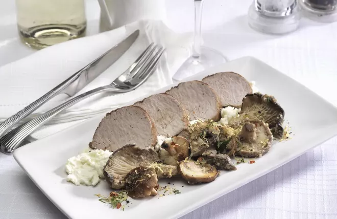 Pork tenderloin slices on ricotta beside a variety of mushrooms