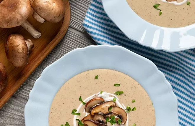 two white bowls housing cream of mushroom soup with mushroom topping