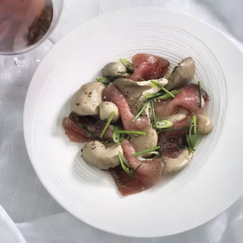 Cured Tuna with Oyster Mushrooms and Green Onion on a White Plate