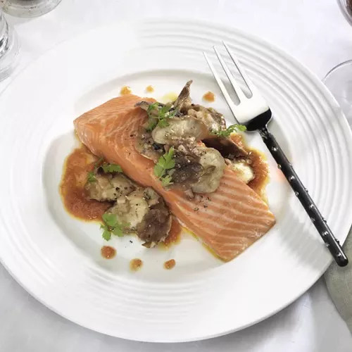 Cooked Salmon on white plate with Shiitake Mushrooms over top