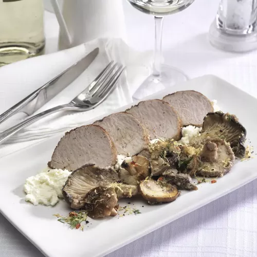 Pork tenderloin slices on ricotta beside a variety of mushrooms